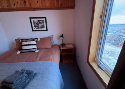 Bedroom 4 at Stay by the Sea B&B in Iqaluit with a queen bed and partial ocean view through the window.