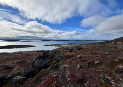 Rocky Arctic tundra overlooking the calm waters of Frobisher Bay under a wide sky in Iqaluit, Nunavut.