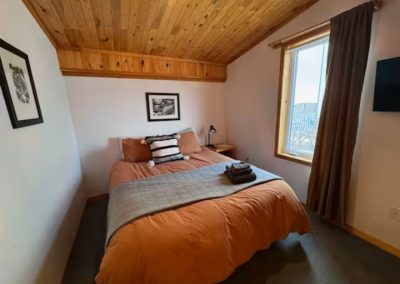 Room 4 at Stay by the Sea B&B in Iqaluit featuring a cozy queen bed, wooden dresser, and cable TV.
